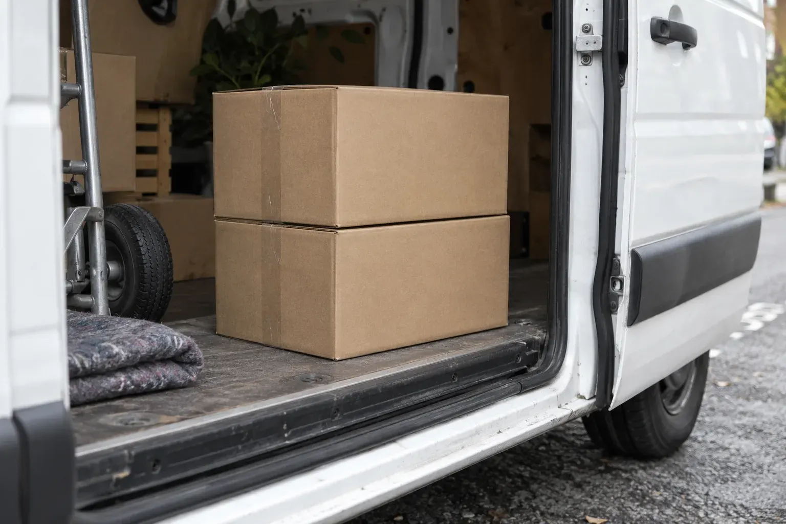 Two identical sealed cartons of packing supplies sit stacked on the floor of an open delivery van.